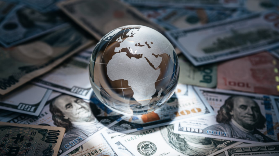 Glass globe sitting on top of 100 dollar bills and bills of other currencies