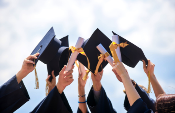 Graduates hold up their caps