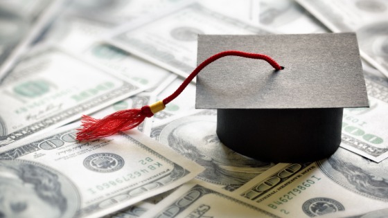 Graduation cap on top of 100 dollar bills