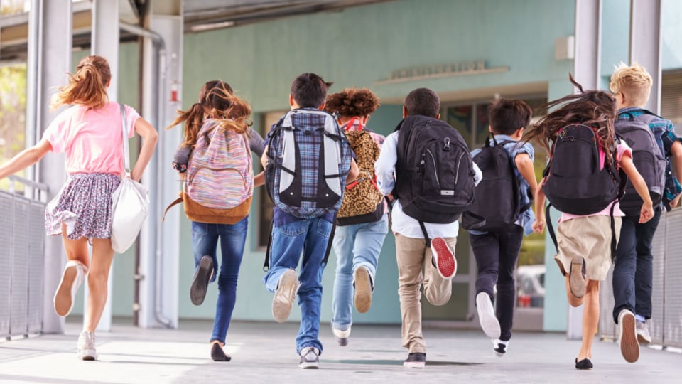 Group of elementary school students leaving school for summer.