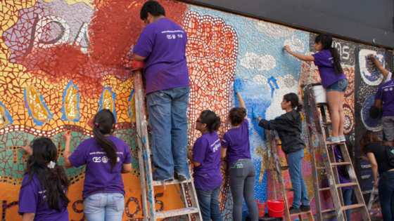 Group of students, supervised by their teacher, making a colorful mosaic on a wall of Pilsen Historic District