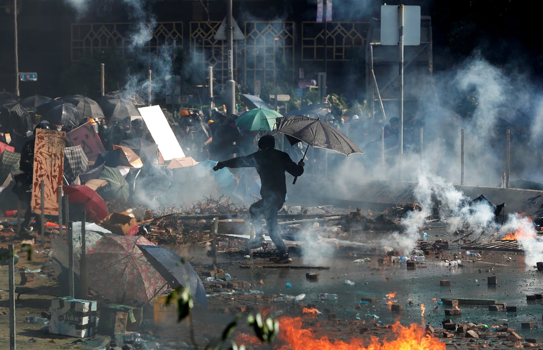 A protester with an umbrella runs for cover during clashes with police outside Hong Kong Polytechnic University (PolyU) in Hong Kong, China November 17, 2019. REUTERS/Adnan Abidi
