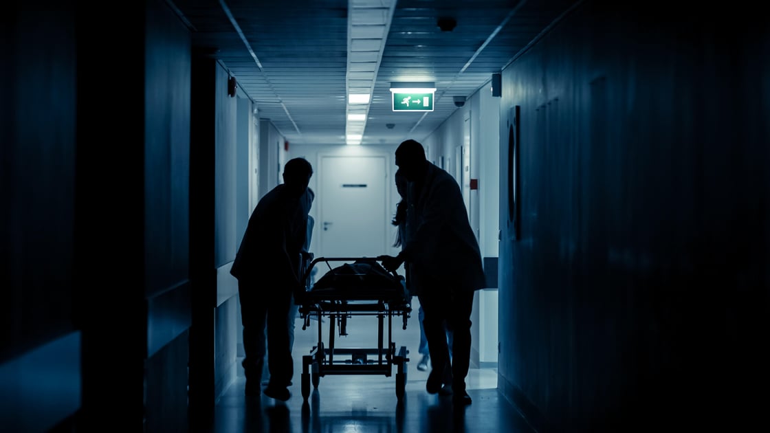 Hospital staff push a gurney through a hospital corridor