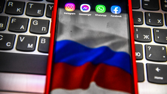 Icons of Instagram, Messenger, WhatsApp, and Facebook are displayed on a smartphone screen with the background of the Russian flag