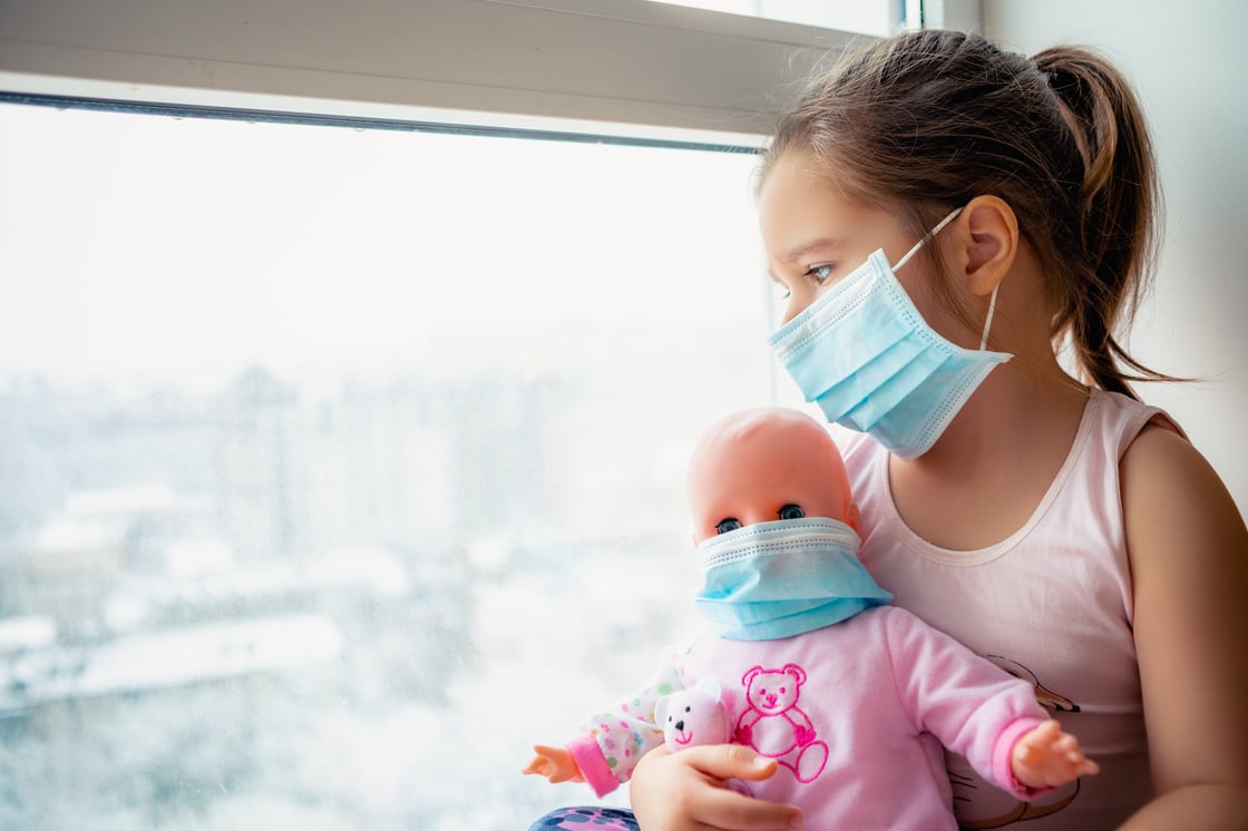 Little girl with surgical mask holding a baby doll with surgical mask. 