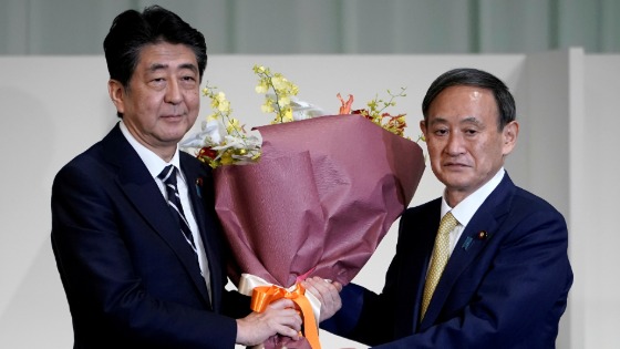 Japanese Chief Cabinet Secretary Yoshihide Suga presents Prime Minister Shinzo Abe with flowers