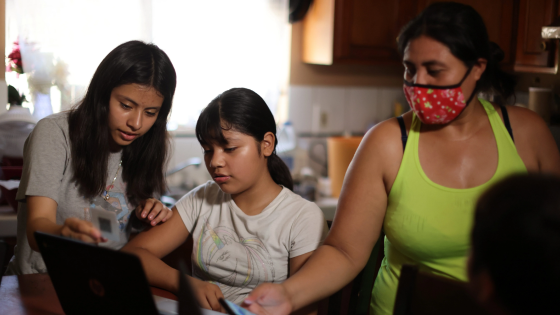 Keiley Flores, 13, Andrea Ramos, 10, and Alexander Ramos, 8, work on school-issued computers with unreliable internet connectivity, as their mother Anely Solis, 32, tries to connect them to her mobile hotspot