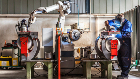 Man and robotic machine work together inside industrial building.