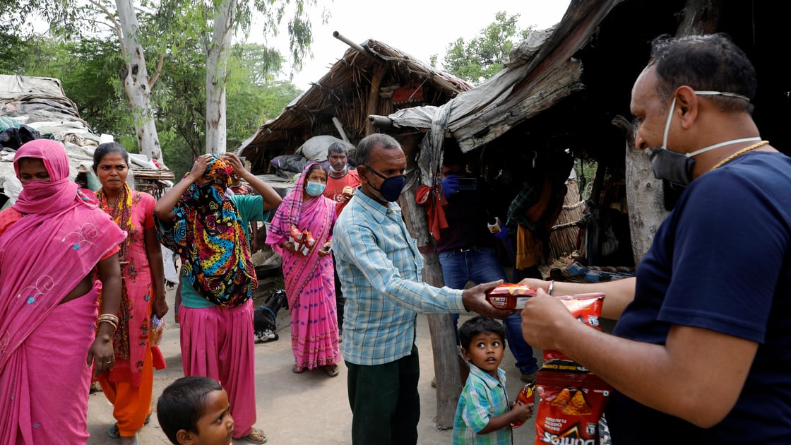 Man distributes food in slum along Yamuna River