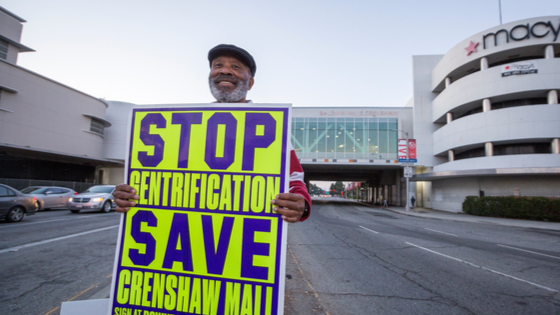 Man holding sign to save the Crenshaw Mall