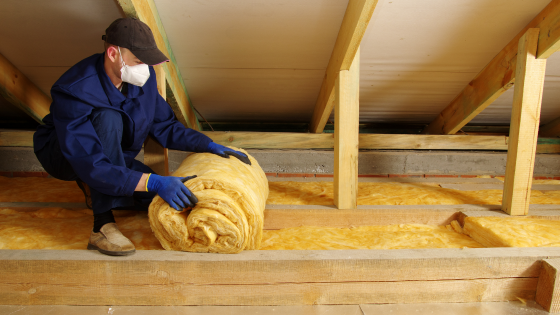 Man installing thermal insulation layer under the roof