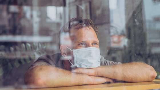 Man looks out window amid COVID-19 pandemic.