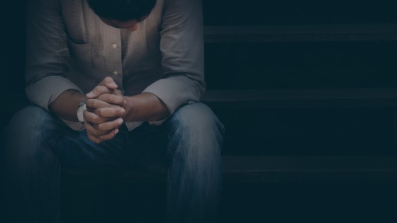 Man with bowed head and clasped hands