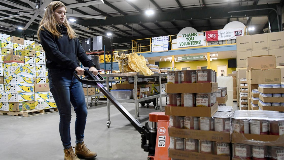 Megan Sussman a volunteer with AmeriCorps moves cans of food at MANNA FoodBank