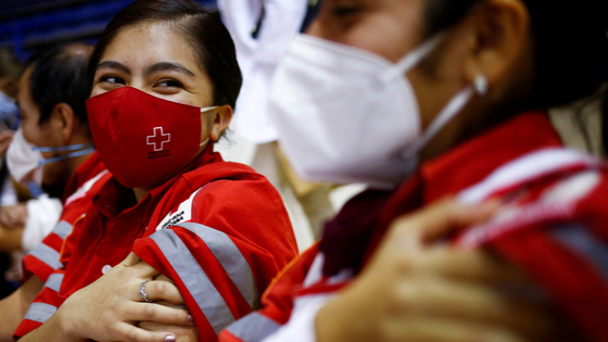 Mexican Red Cross paramedics press on her arm after receiving a booster shot of the AstraZeneca COVID-19 vaccine.