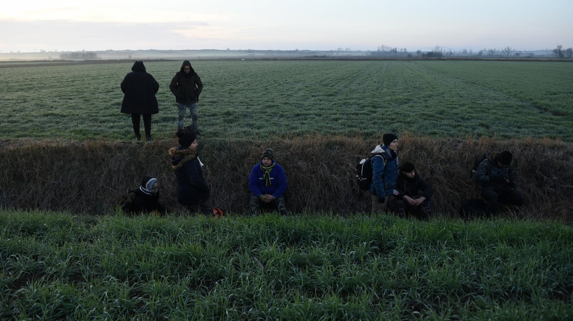 Migrants rest in a ditch after crossing from Turkey to Greece