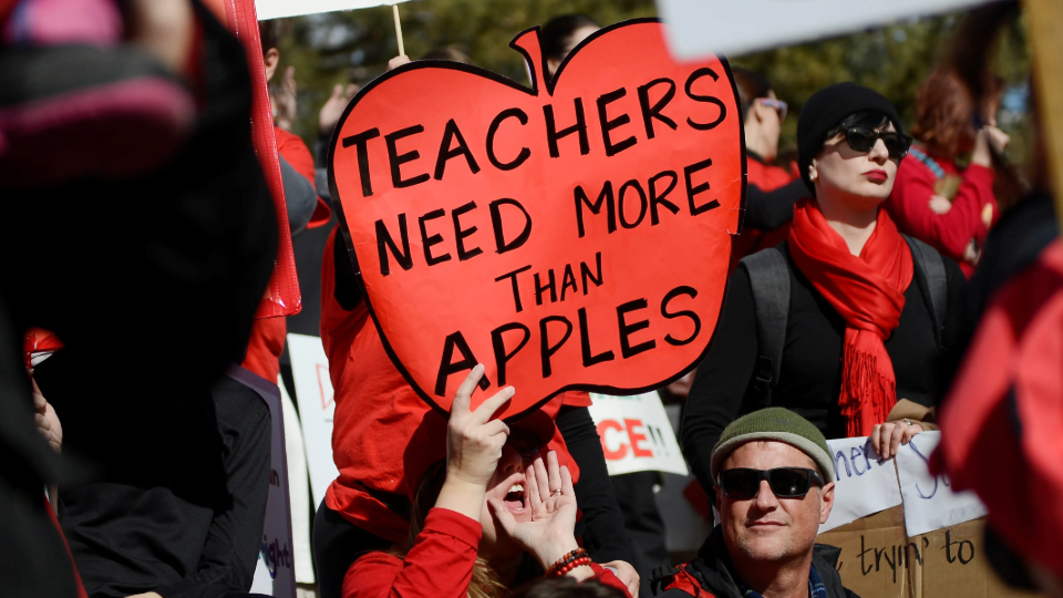 Munroe Elementary teacher Melissa Curry holds a sign during a rally across from the Colorado State Capitol