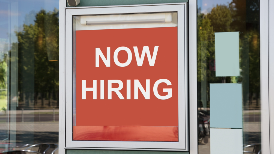 Now hiring sign hanging outside of an office building