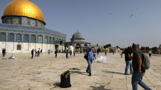 Palestinians react during clashes with Israeli police at the compound that houses Al-Aqsa Mosque