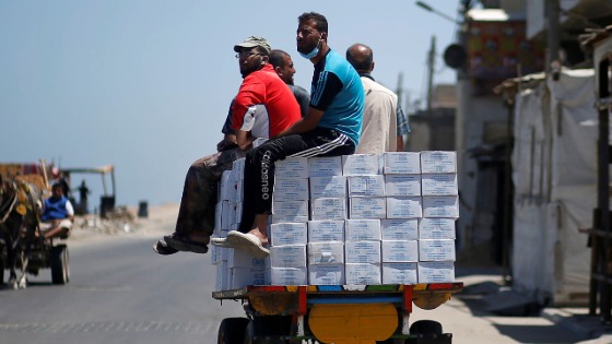 Palestinians ride a cart transporting aid supplies distributed by UNRWA