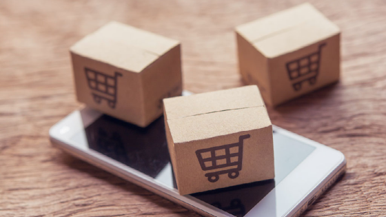 Paper cartons or parcel with a shopping cart logo and smartphone on wood table top