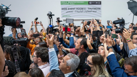 Participants and journalists take photos and videos at the U.N. climate summit (COP27).