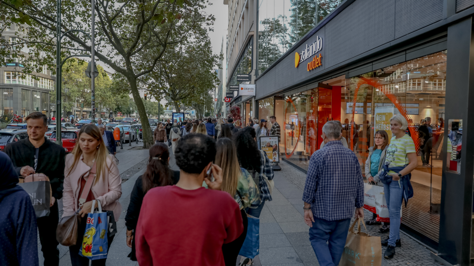 People in Berlin walk outside of a shop.