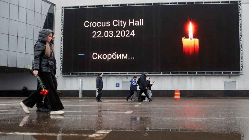 People lay flowers at a makeshift memorial to the victims of a shooting attack at a concert hall outside Moscow