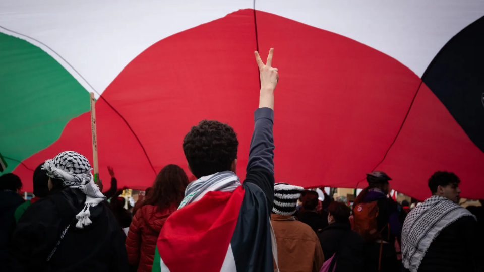 People march under an large Palestinian flag against Israels planned ground invasion of Rafah, Gaza