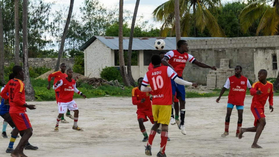 People play a soccer match on rough ground