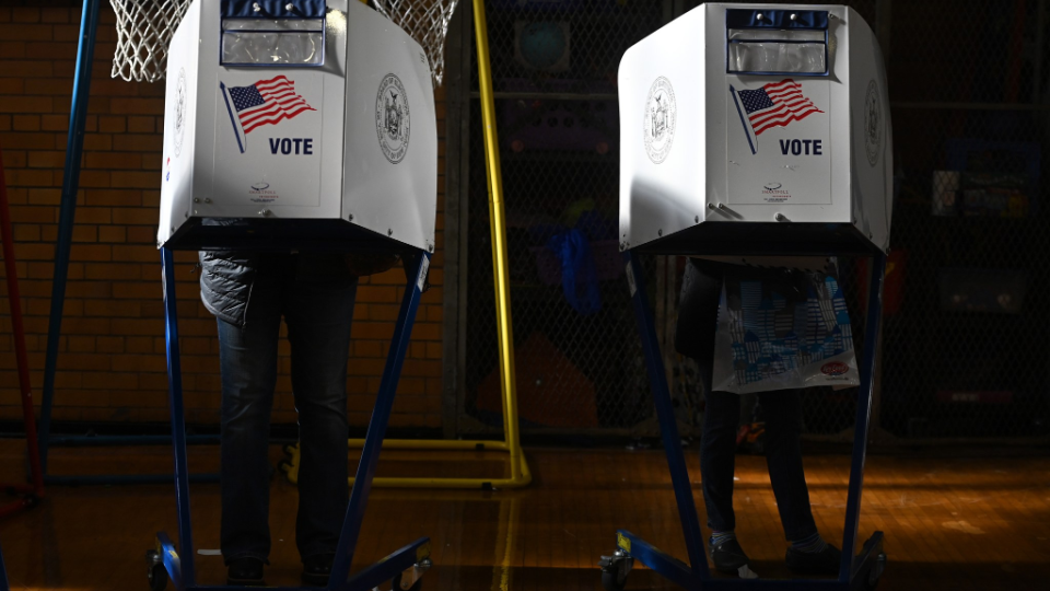 People stand behind privacy booths to fill out their ballot before casting their votes for the 2022 midterm election,