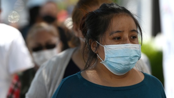 People suffering from food insecurities line up to receive food donations along Northern Boulevard in the Queens