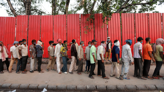 People wait in a queue to receive free food during a COVID-19 lockdown in New Delhi