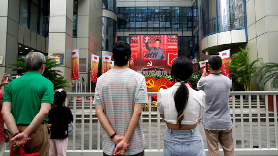 People watch a giant screen broadcasting Chinese President Xi Jinping