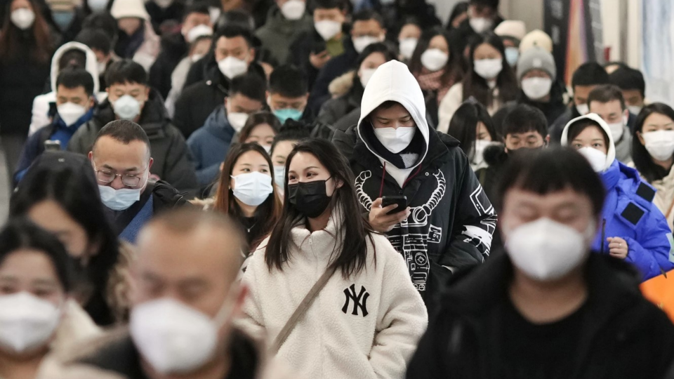 People wearing face masks walk in a subway station in Beijing during rush hour