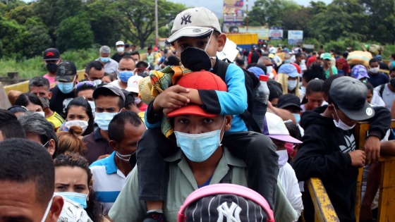 People wearing protective face masks line up to cross the border between Colombia and Venezuela