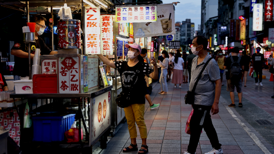 People wearing protective masks pick up their food at a newly opened night market