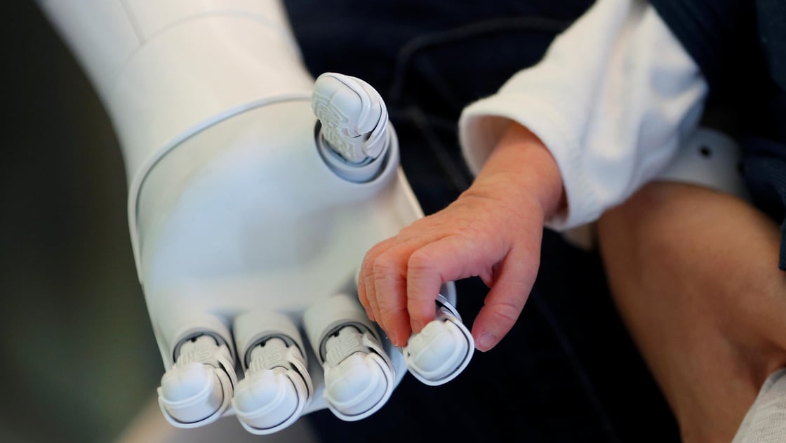 Pepper the robot holds the hand of a new born baby