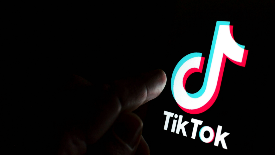 Person going to touch TikTok logo on screen