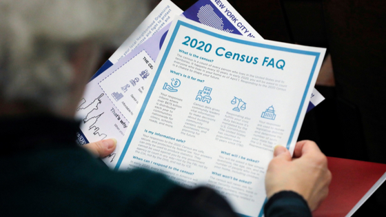 Person holding 2020 Census FAQ page.