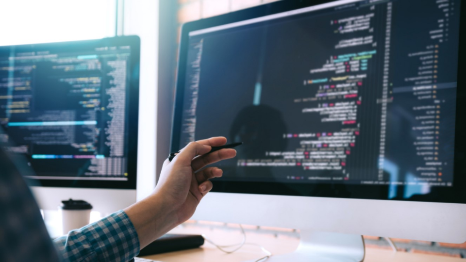 Person looking at code on large computer screens