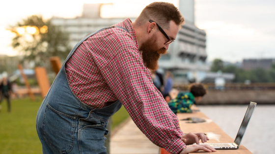 Person looks at laptop in an outdoor setting