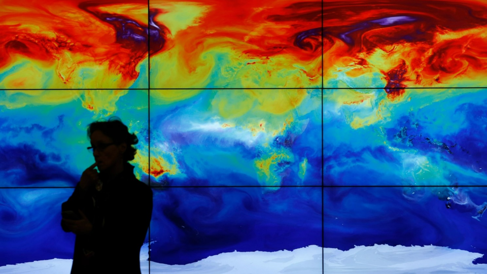 Person standing in front of a thermal map of the world