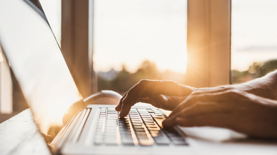 Person using laptop with sun in the background