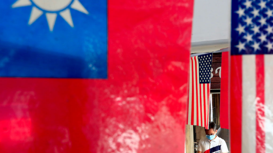 Person with face mask walks past US and Taiwan flags outside a restaurant