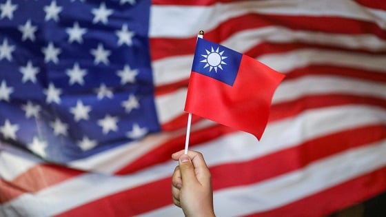 Protester holds a Taiwan national flag as an U.S. flag flutters in the background.