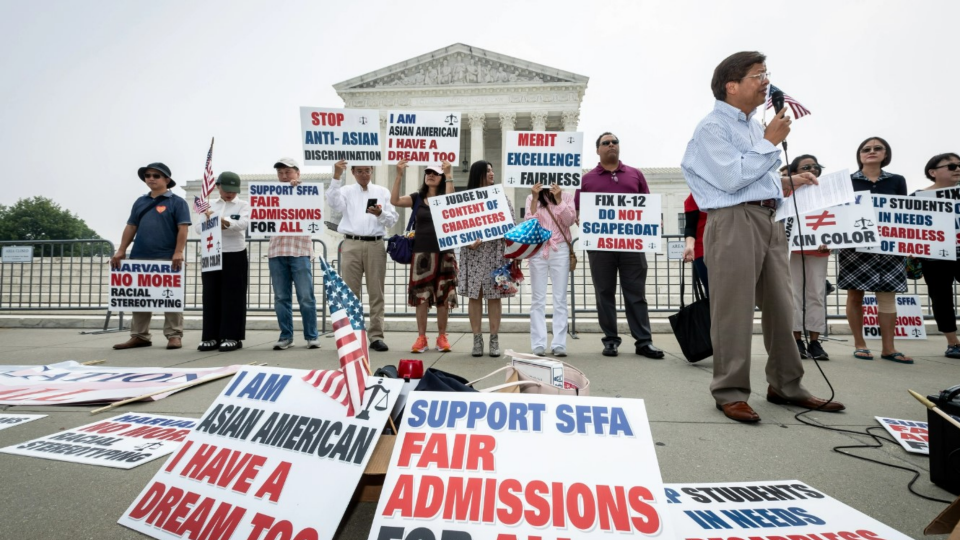 Protesters hold up signs about affirmative action in front of the Supreme Court