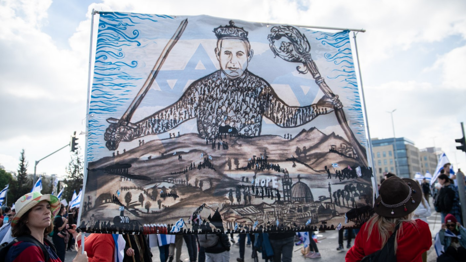 Protestors against judicial reforms hold a hand-painted sign of Leviathan cover with the face of Prime Minister Benjamin Netanyahu