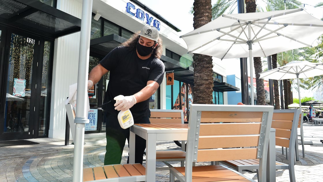 An employee cleans an outdoor seating area in Coral Gables, Florida.