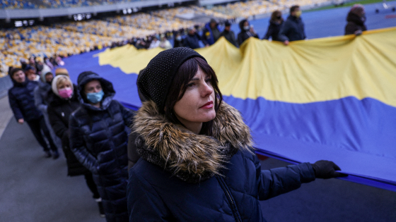 Residents carry Ukrainian national flag as they gather in the Olympic Stadium to mark the Unity Day